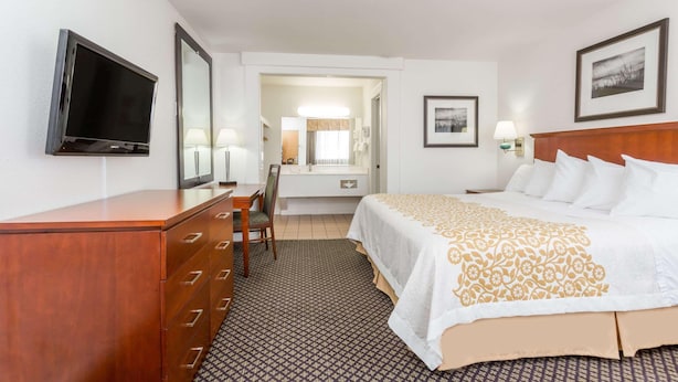A hotel room with a bed, a TV, a desk, and a bathroom visible through an open door. - Days Inn By Wyndham Kimball (Kimball)