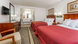 A hotel room with two beds, a desk, a chair, a TV, and a bathroom visible through an open door. - Days Inn By Wyndham Kimball (Kimball)
