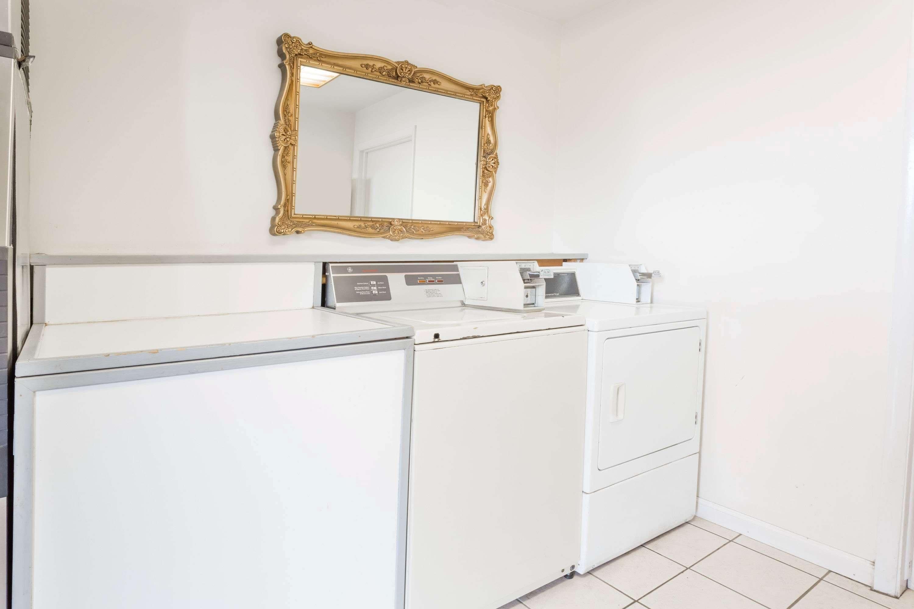 Un espace buanderie comprenant un lave-linge blanc, un sèche-linge et un grand miroir fixé au mur.