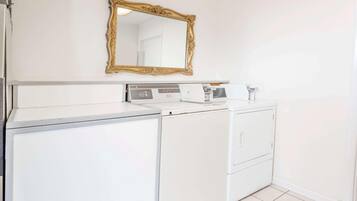 Un espace buanderie comprenant un lave-linge blanc, un sèche-linge et un grand miroir fixé au mur.