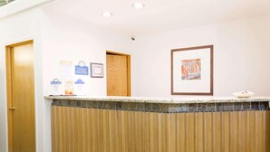 A reception area with a wooden reception desk, a framed artwork on the wall, and a sign for Days Inn. - Days Inn By Wyndham Kimball (Kimball)