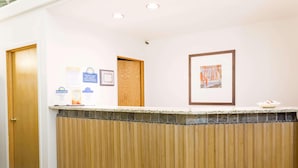 A reception area with a wooden reception desk, a framed artwork on the wall, and a sign for Days Inn. - Days Inn By Wyndham Kimball (Kimball)
