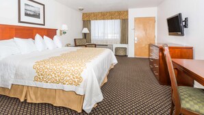 A hotel room with a large bed, a desk, a chair, a TV, and a door. - Days Inn By Wyndham Kimball (Kimball)