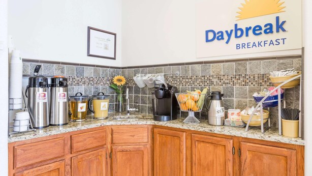 A kitchen with a Daybreak Breakfast sign, stainless steel appliances, and a tiled backsplash. - Days Inn By Wyndham Kimball (Kimball)
