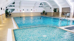 Ein Innenpool mit gefliesten Wänden, klares blaues Wasser und einige Schwimmer.