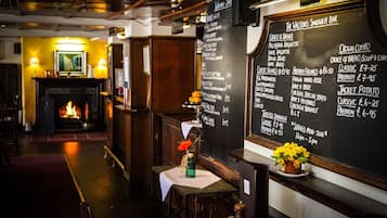A restaurant interior with a blackboard menu listing sandwiches, salads, and drinks. A fireplace is visible in the background.