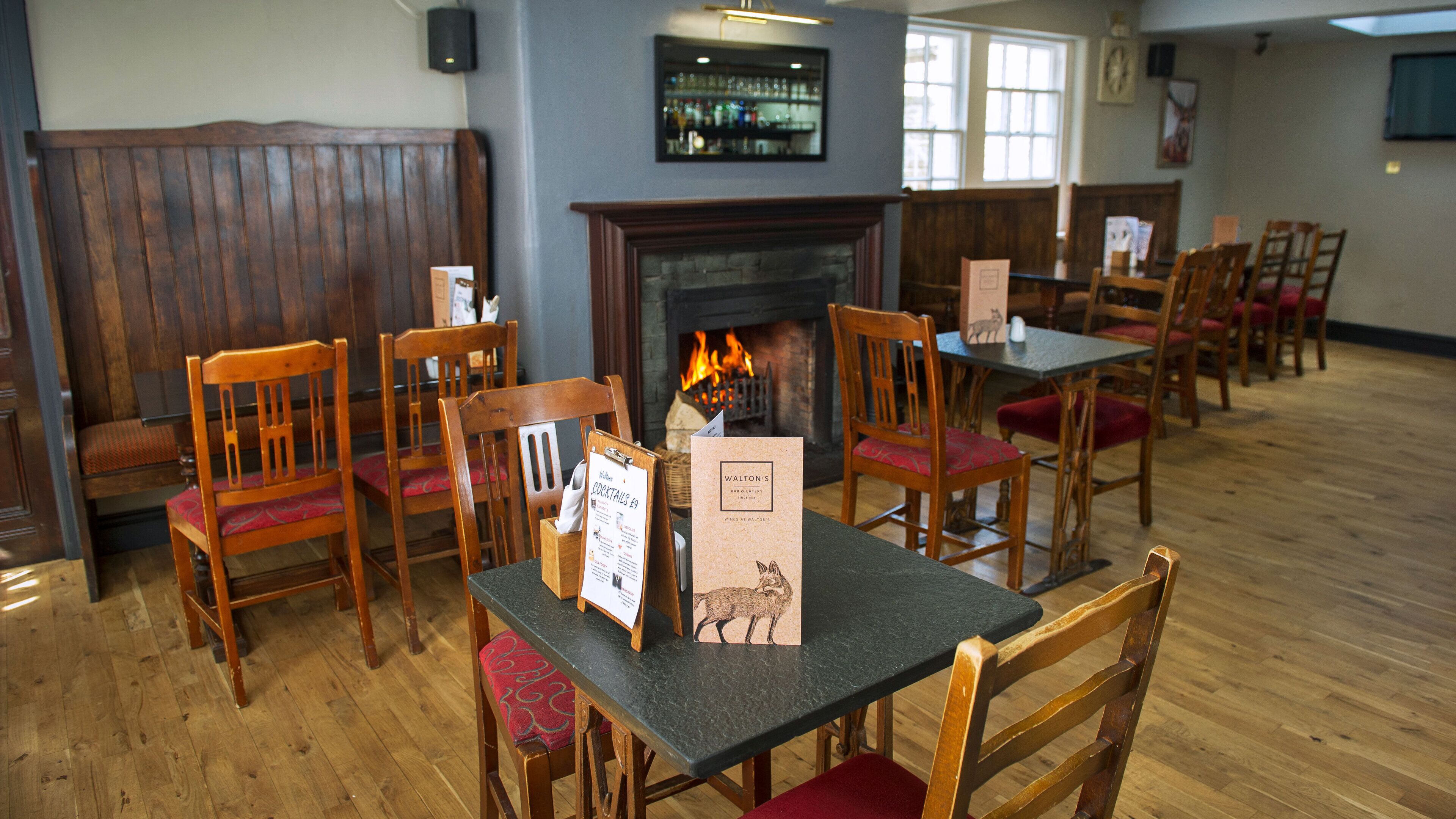 A restaurant interior with wooden furniture, a fireplace, and a menu stand.