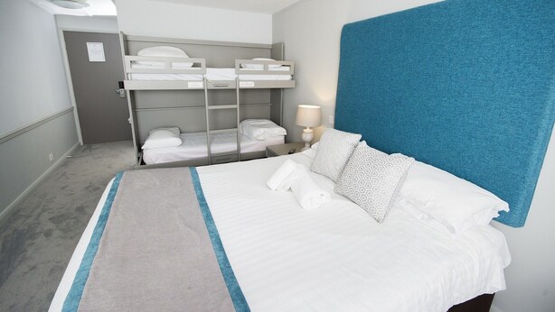 A hotel room with a large bed, a bunk bed, a desk, and a lamp. - Crown Hotel Wetheral (Carlisle)