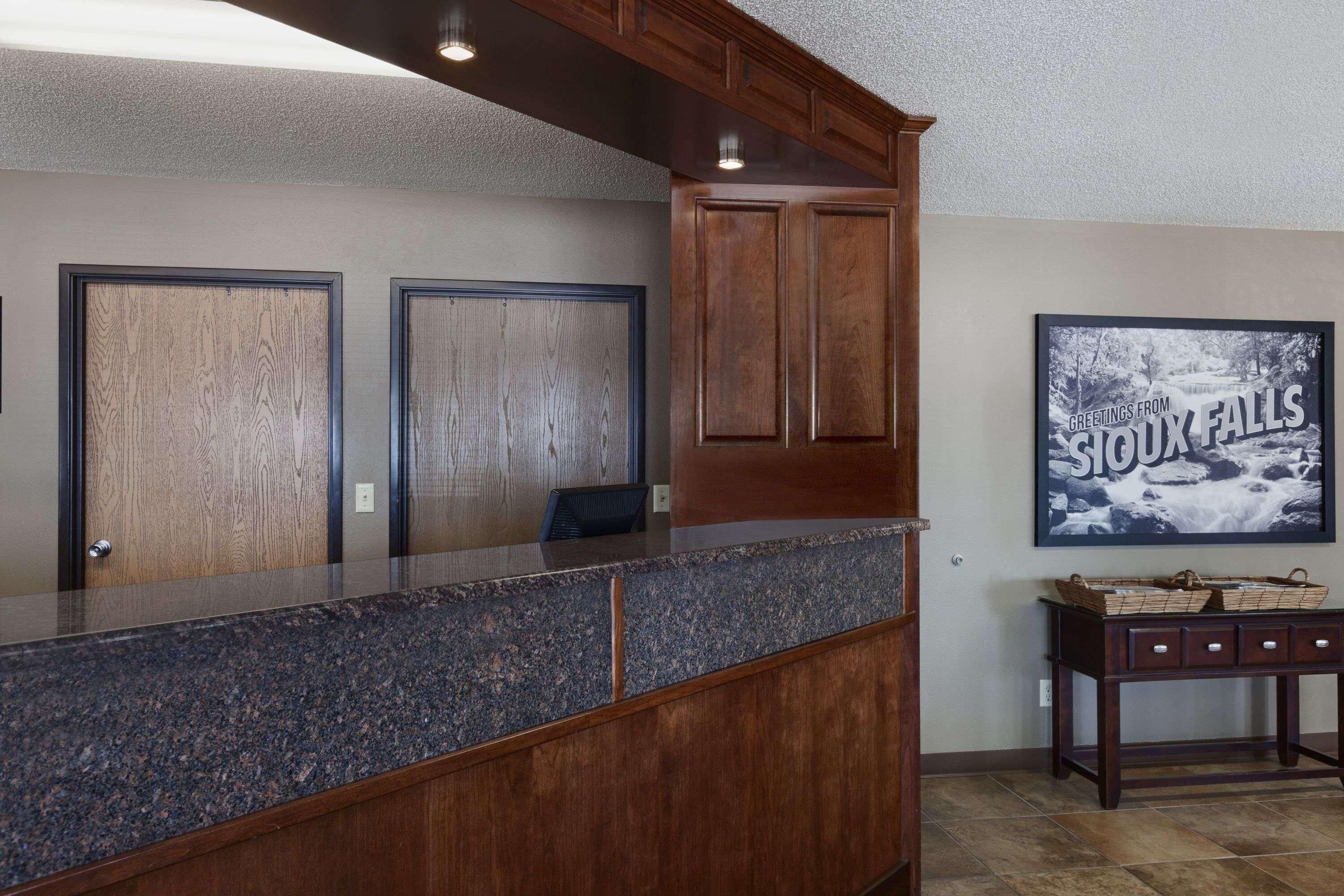 A reception area with a marble counter, wooden cabinets, and a framed picture of a waterfall.