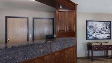 A reception area with a marble counter, wooden cabinets, and a framed picture of a waterfall.