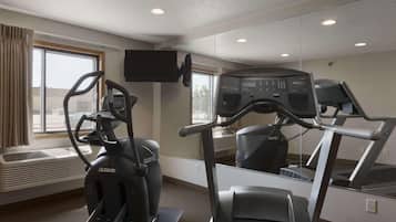 A gym with an elliptical machine, a treadmill, and a mirrored wall.