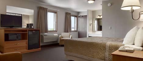 A hotel room with a bed, a desk, a television, a minibar, and a bathroom.