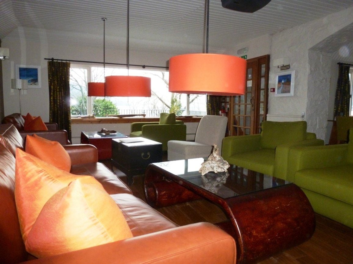 A living room with leather sofas, a glass coffee table, and green armchairs.