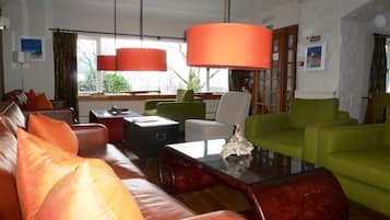 A living room with leather sofas, a glass coffee table, and green armchairs.