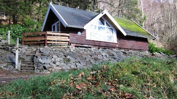 A cabin with a stone foundation, wooden walls, a sloped roof, and a small porch.