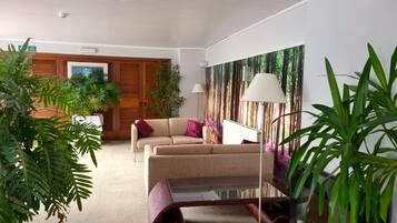 A modern living room with a sofa, a coffee table, and a large painting of a forest.