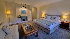 Een hotelkamer met een bed, een bank, een salontafel, een bureau en een lamp.