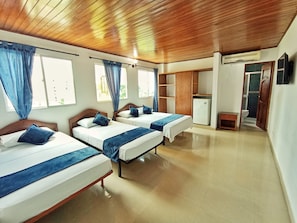 A hotel room with two beds, a wardrobe, a small table, and a shower area.