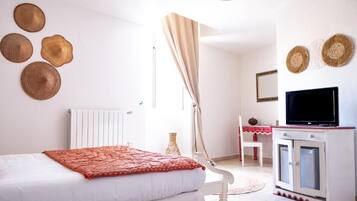 Un dormitorio con cama, televisión, escritorio y adornos en la pared.