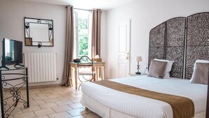 A bedroom with a bed, a desk, a chair, a TV, a radiator, and a window with curtains. - La Bastide De Cabezac (Bize-Minervois)