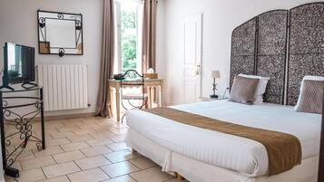 Een slaapkamer met een bed, een bureau, een stoel, een televisie, een radiator en een raam met gordijnen.