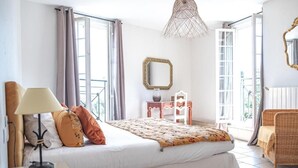 Un dormitorio con cama, lámpara, cómoda, espejo y silla.