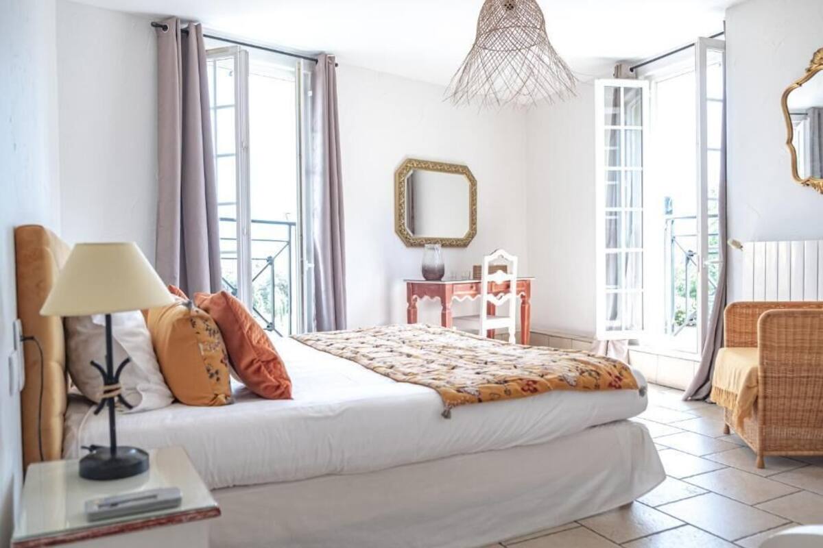 A bedroom with a bed, a lamp, a dresser, a mirror, and a chair.