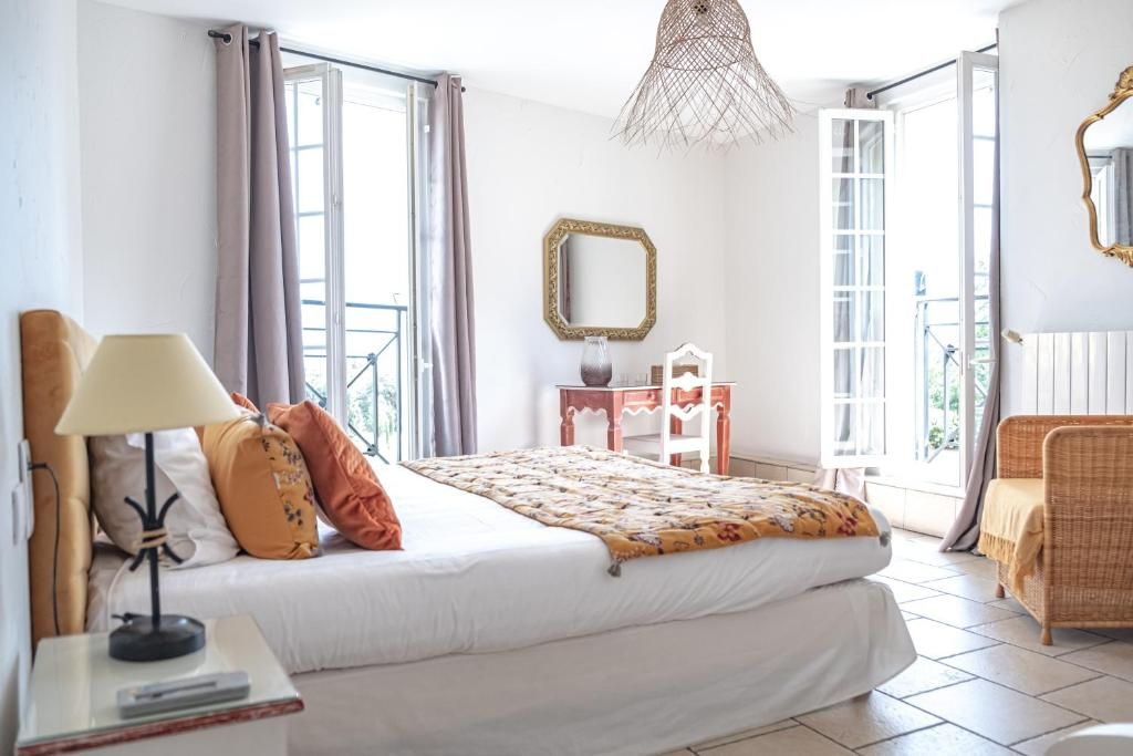 Een slaapkamer met een bed, lamp, dressoir, spiegel en stoel.