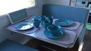 Un coin repas avec une table dressée pour quatre personnes, agrémenté d’assiettes, de bols et de tasses bleus.