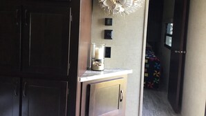 Een keuken met donkere houten kastjes, een marmeren aanrechtblad, een decoratieve schelpenkrans en een klein raam.