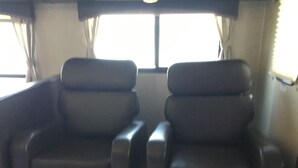 Een kamer met twee lounge fauteuils en een raam met gordijnen.