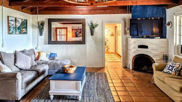 Ein gemütliches Wohnzimmer mit Kamin, einer Couch, einem Couchtisch und einem an der Wand montierten Fernseher.