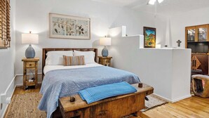 Ein Schlafzimmer mit einem hölzernen Bett, zwei Nachttischlampen, einem Deckenventilator und einem großen Fenster mit Jalousien.