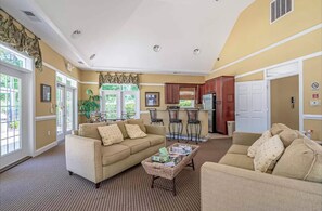 Relax in this spacious living area with a sofa set and coffee table, featuring a high ceiling and large window.