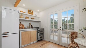A kitchen with white appliances, wooden cabinets, and a large window. - Casa Blanca, Secluded Mediterranean Retreat in RSF (Rancho Santa Fe)