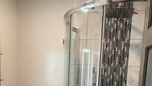 A modern bathroom with a glass-enclosed shower, a toilet, and a tiled floor.