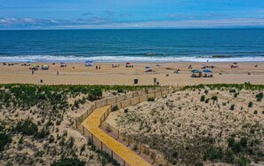A beach with a wooden boardwalk leading to the water, surrounded by dunes and sparse vegetation. - Relax by the Shore – 3BR Home, Just Minutes to Beach (Ocean City)