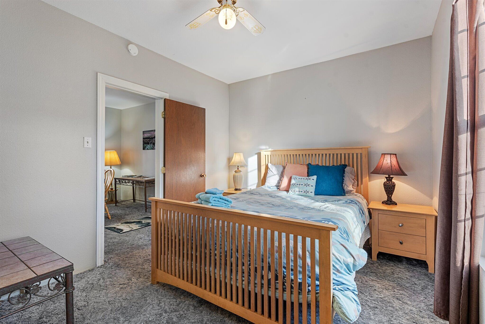 A bedroom with a wooden bed, bedside tables, a desk, and a chair.