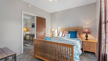 A bedroom with a wooden bed, bedside tables, a desk, and a chair.