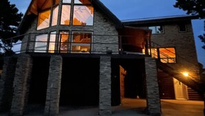 Una amplia casa de piedra con un ático destacado y ventanas grandes, que cuenta con un garaje y una escalera que lleva a un segundo nivel.
