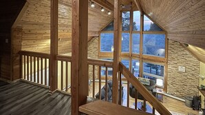 Amplia habitación en ático con vigas de madera, un tragaluz grande y vistas al exterior.