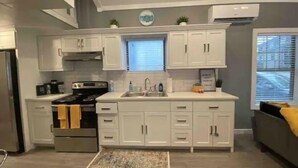 Une cuisine moderne avec des meubles blancs, une cuisinière en acier inoxydable et une fenêtre équipée de stores.