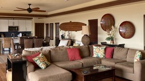 Ein geräumiges Wohnzimmer mit Ecksofa, Couchtisch und Deckenventilator.