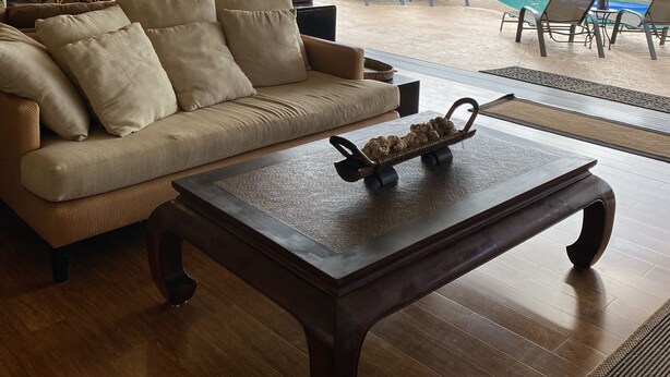 Ein Wohnzimmer mit einer Couch, einem Couchtisch und Blick auf einen Außenpool.