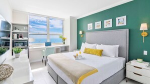 Habitación de hotel moderna con una cama grande, un escritorio y vista al mar.