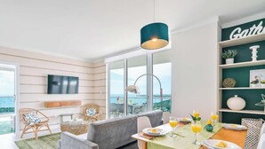 A modern room with a large window, a dining table set with plates and glasses, and a view of the sea. - Chic Grove Apartment | Floor-to-Ceiling Glass (Miami)
