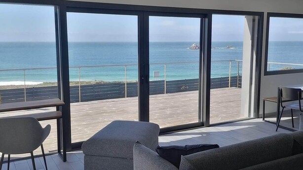 A modern living room with large windows overlooking a beach and ocean. - 4*house ON THE SEAFRONT WITH AN IMPREGNABLE VIEW of IROISE SEA INTERIOR SPA GR34 (Plouarzel)