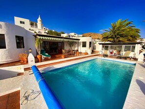 Una piscina amb gandules i una zona de pati coberta.