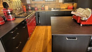 Una cocina moderna con armarios oscuros, una estufa roja y un horno empotrado.