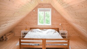 A cozy attic bedroom with a wooden sloped ceiling, a large window, two bedside tables, and a double bed. - Gorgeous home in Markaryd (Markaryd)